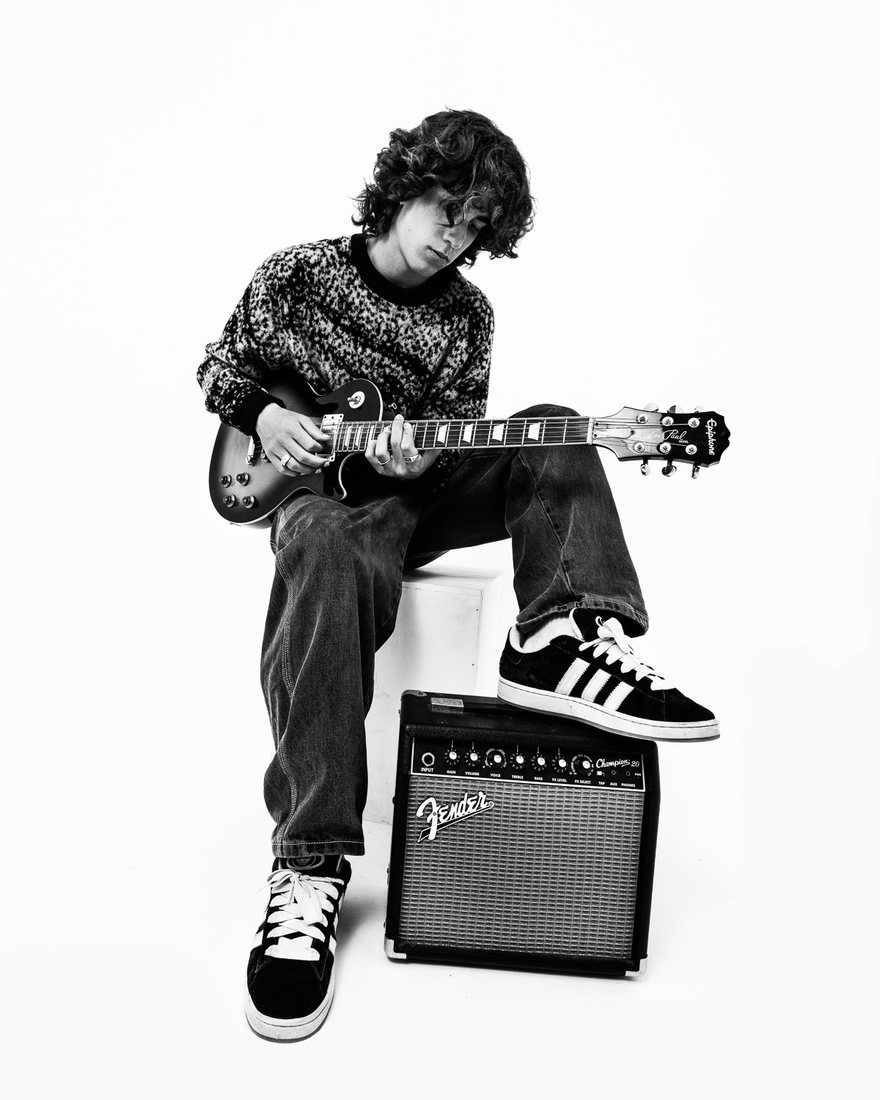 MYLES seated on a Fender amp with guitar